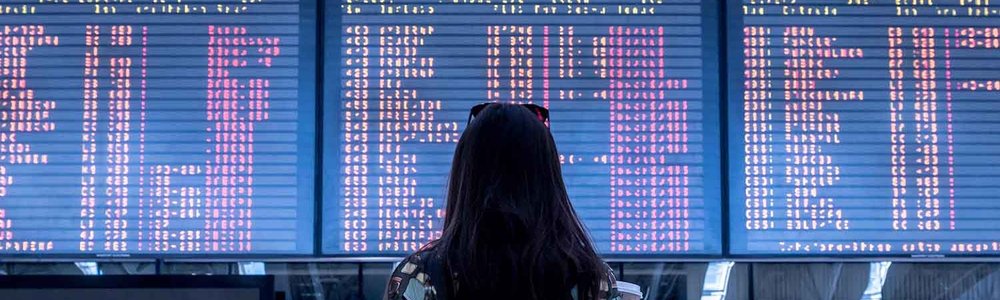 Photo of a lady standing in front of arrival departure board at an airport