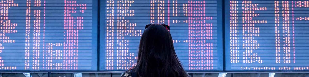 Photo of a lady standing in front of arrival departure board at an airport
