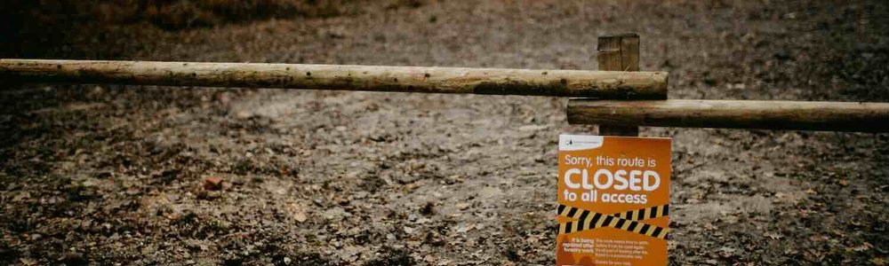 Photo of a barrier in front of a path with a sign saying 'route closed'|