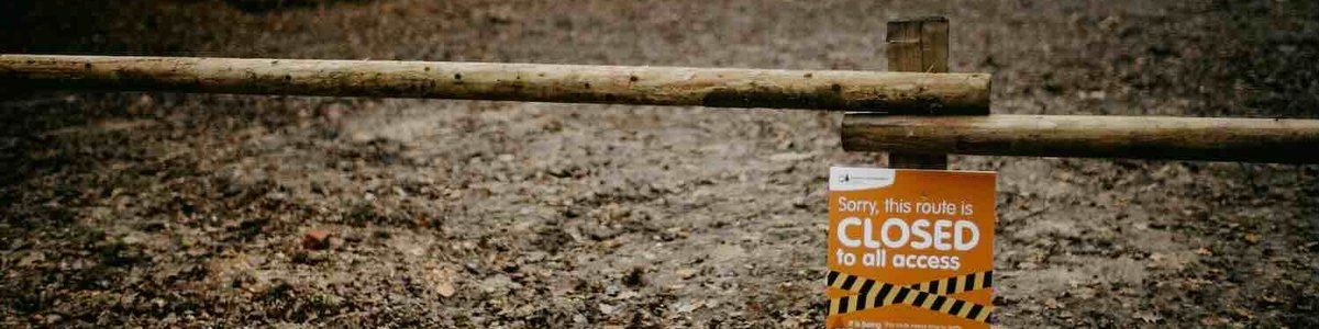 Photo of a barrier in front of a path with a sign saying 'route closed'|