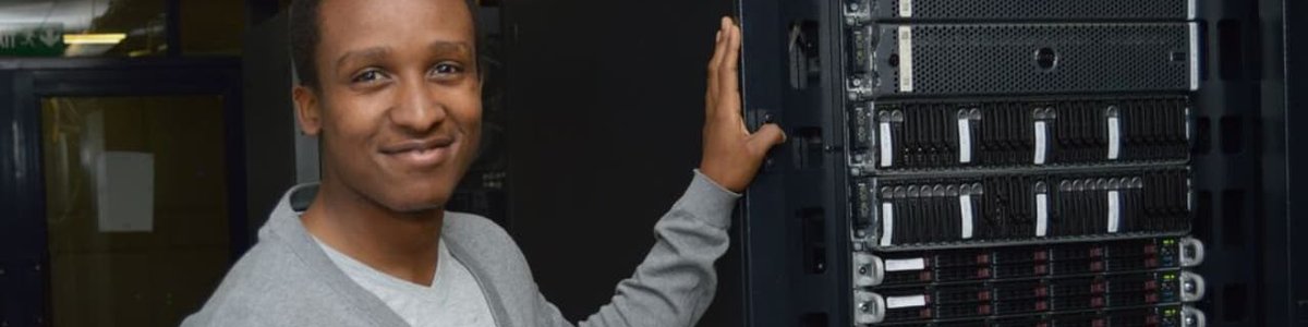 Photo of a person standing in front of a network rack containing an IXP switch||||||