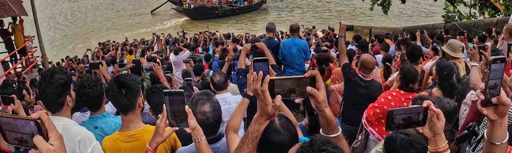 A crowd of people taking photos along a river in India
