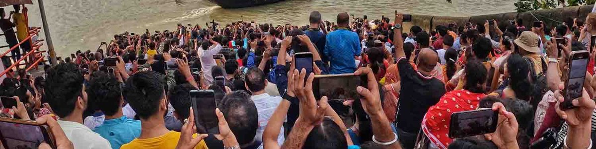 A crowd of people taking photos along a river in India