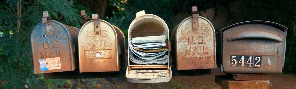 Photo of five mailboxes, one of which is full
