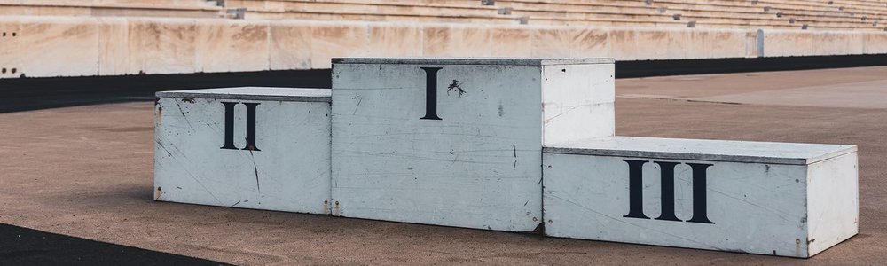 Photo of a first, second and third podium in a stadium|