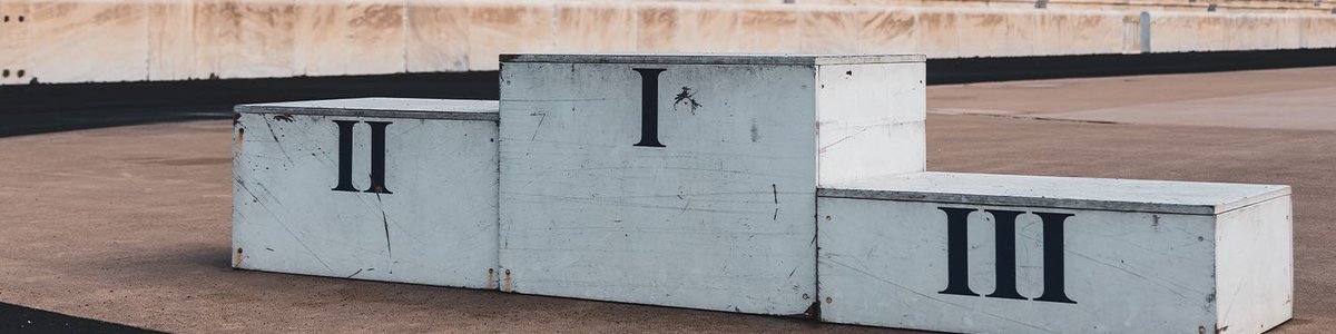 Photo of a first, second and third podium in a stadium|