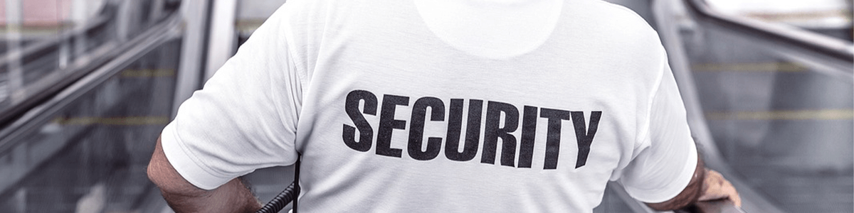 Photo of the back of a man wearing a white shirt that says Security on it|