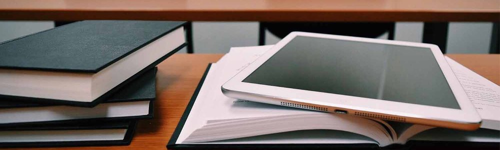 Photo of a stack of books and a tablet