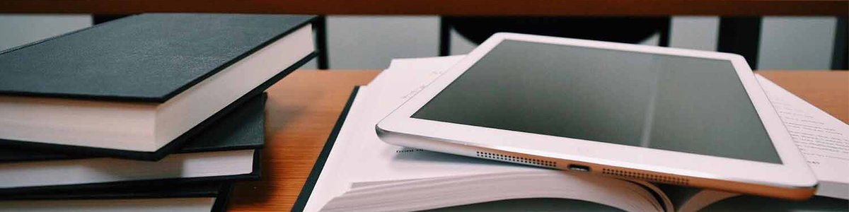 Photo of a stack of books and a tablet