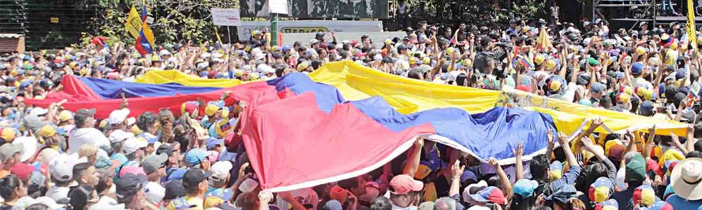 Photo of a crowd holding a large flag of Venezuela||||||