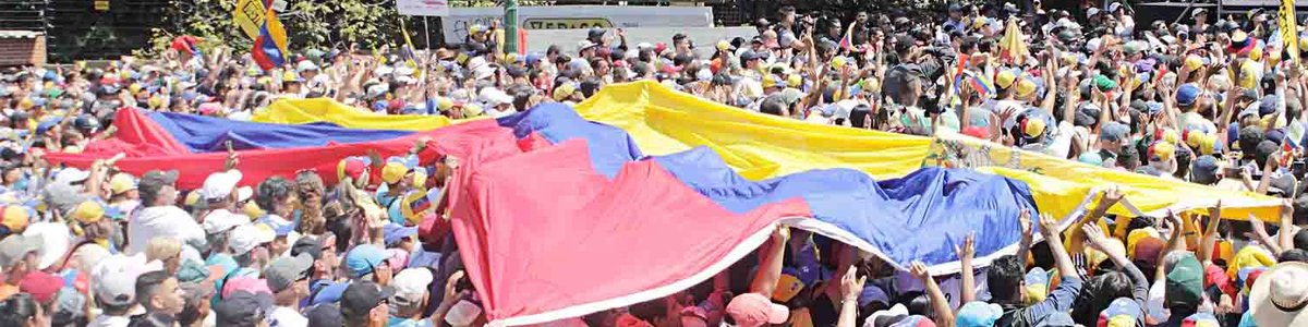 Photo of a crowd holding a large flag of Venezuela||||||