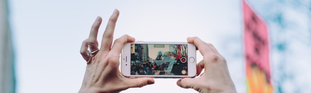 Hands holding a mobile phone, filming during a protest
