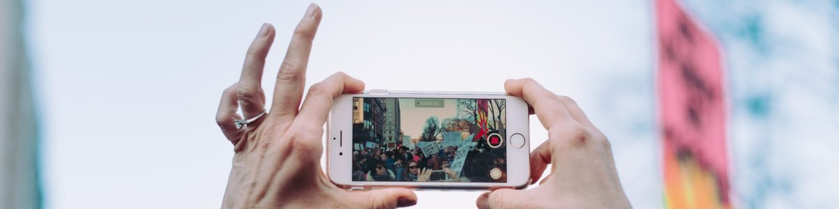 Hands holding a mobile phone, filming during a protest