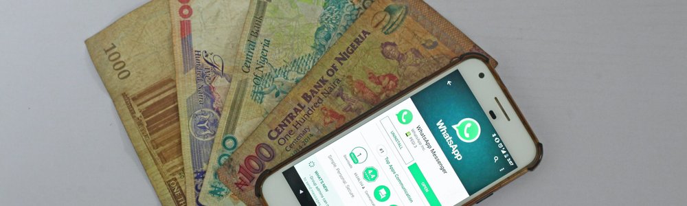 A mobile phone showing whatsapp and Nigerian bank notes||