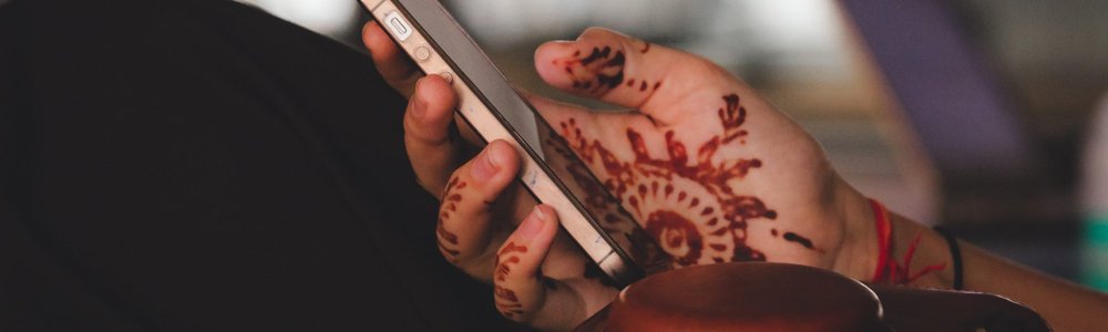 Indian woman's hand with henna holding iphone