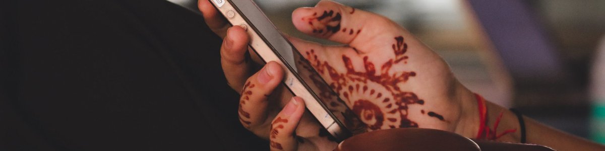 Indian woman's hand with henna holding iphone