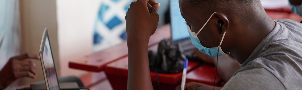 Young African man in mask at laptop|