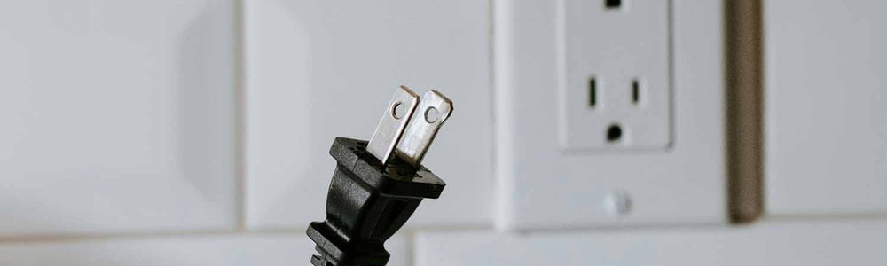 Photo of an emplty power plug and a person holding a power cable