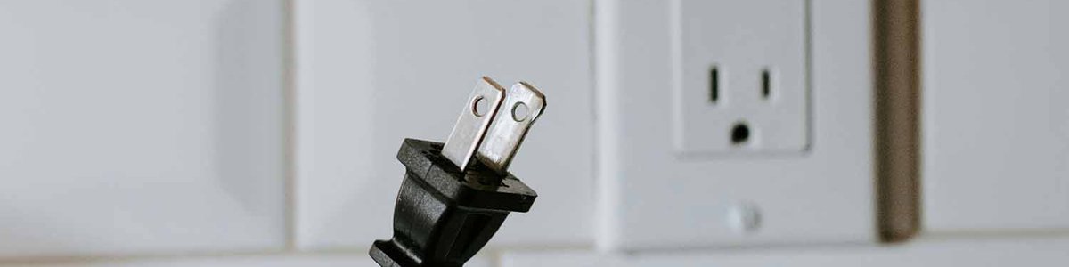 Photo of an emplty power plug and a person holding a power cable