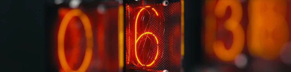 A close up photo of a clock on a table showing six.