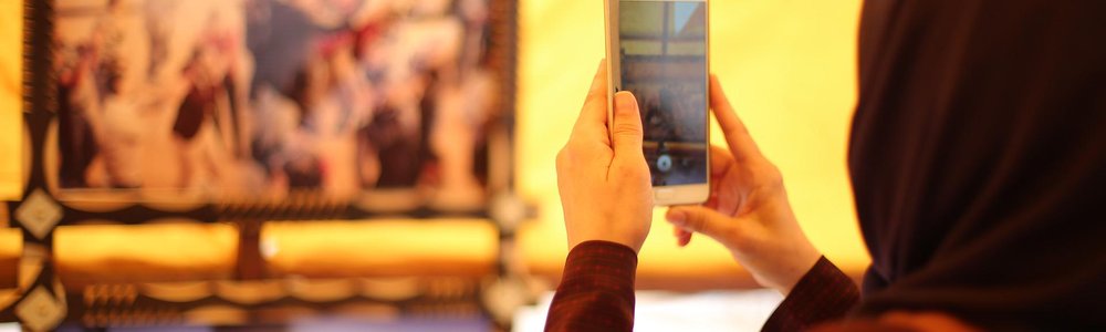Woman in a hijab taking a photo with a mobile phone