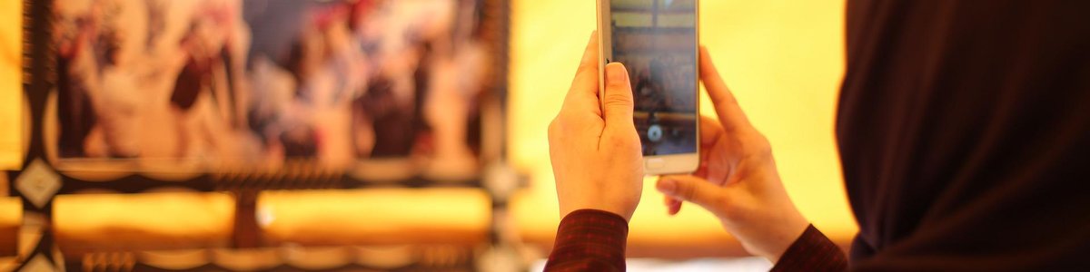 Woman in a hijab taking a photo with a mobile phone