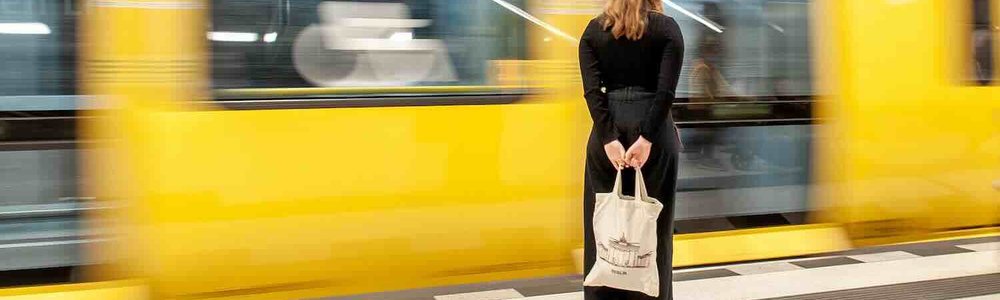 Photo of a woman waiting at a platorms edge as a train goes past