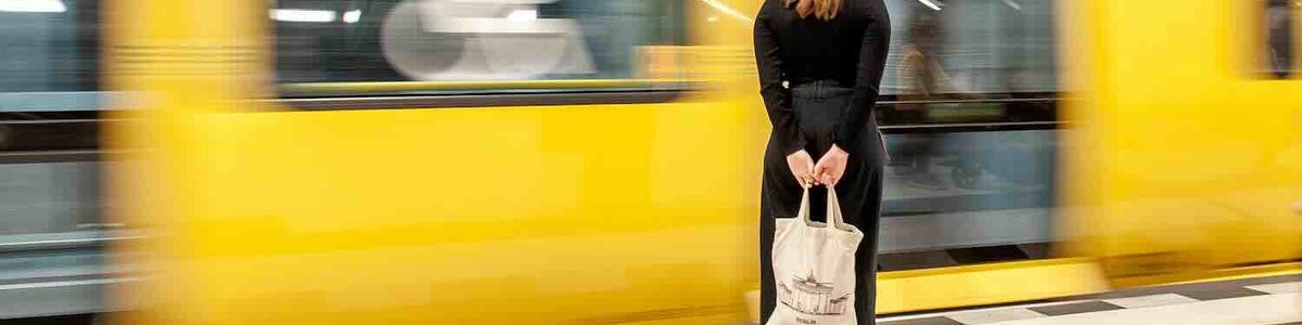 Photo of a woman waiting at a platorms edge as a train goes past