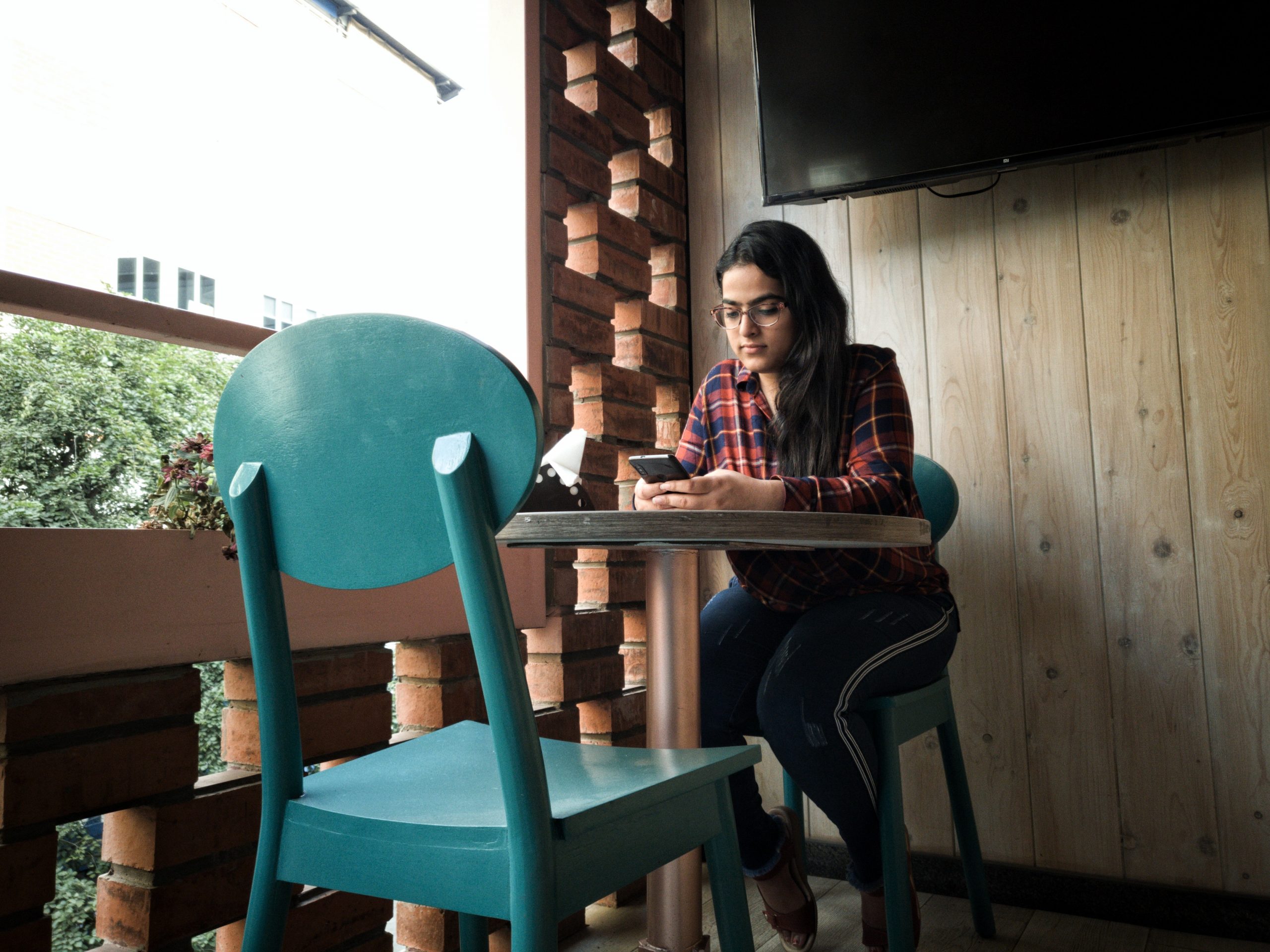 Indian woman in cafe with mobile phone