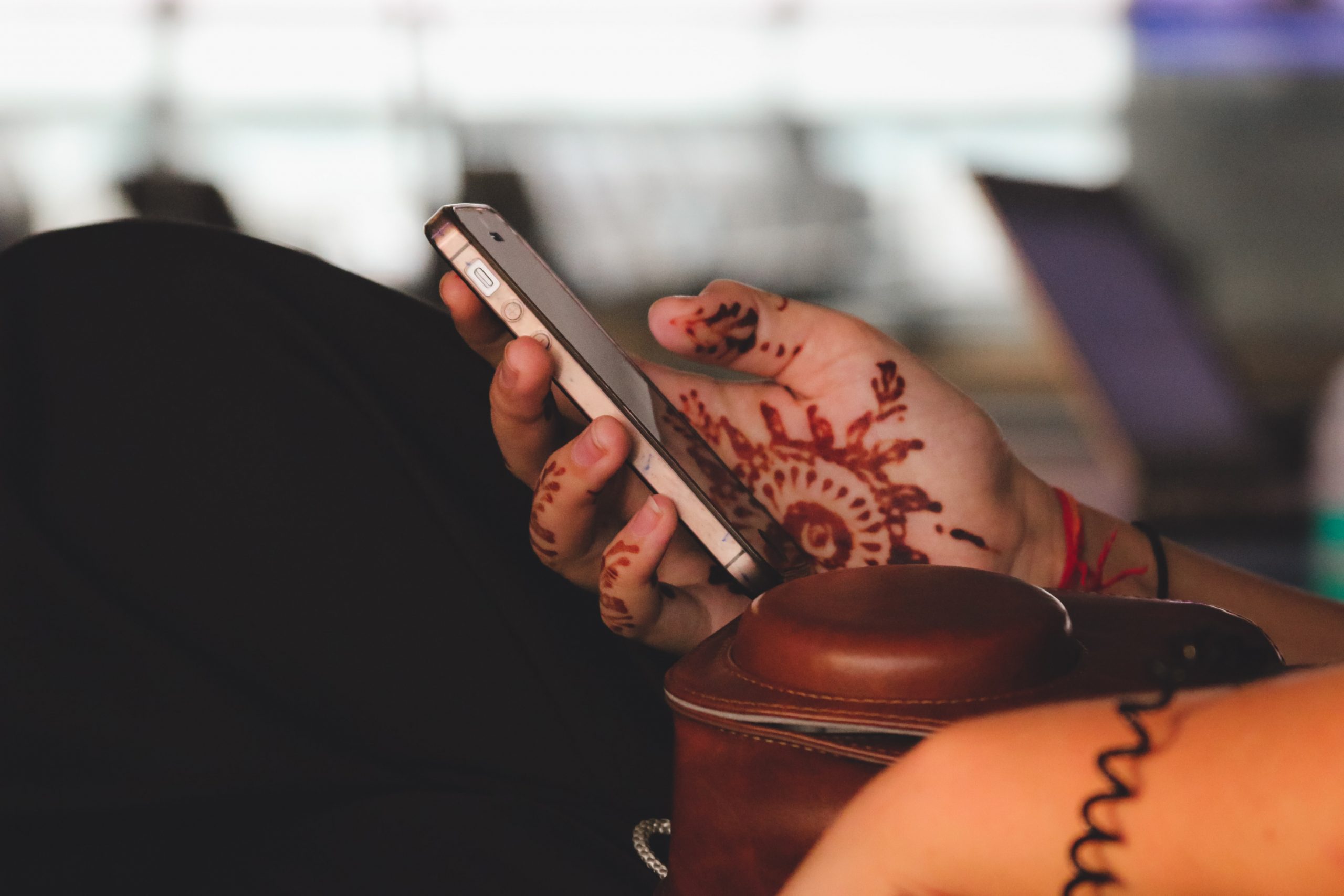 Indian woman's hand with henna holding iphone