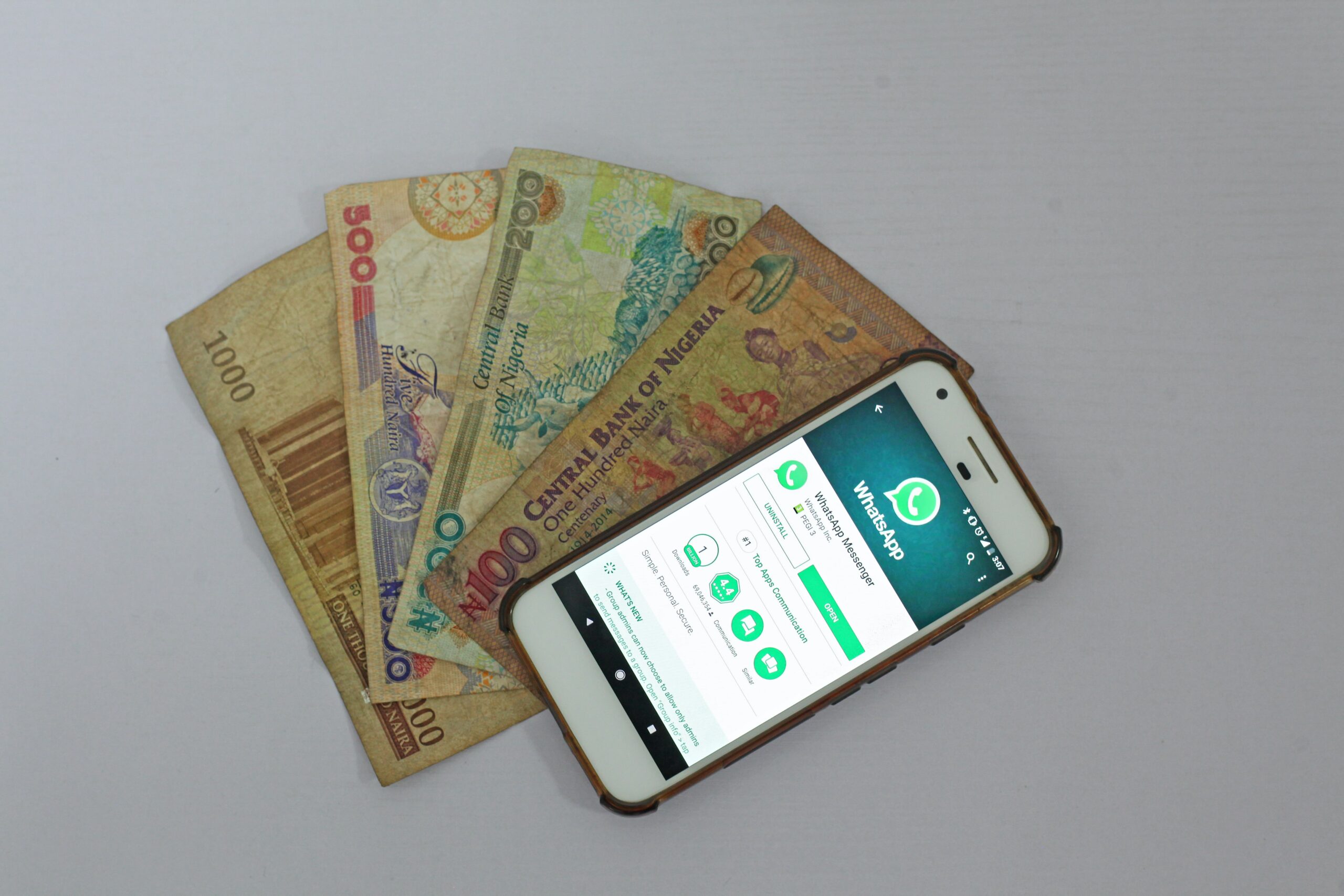 A mobile phone showing whatsapp and Nigerian bank notes
