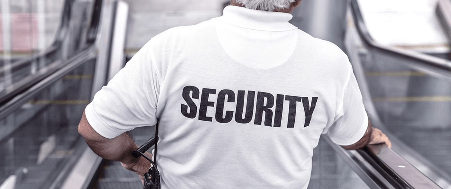 Photo of the back of a man wearing a white shirt that says Security on it