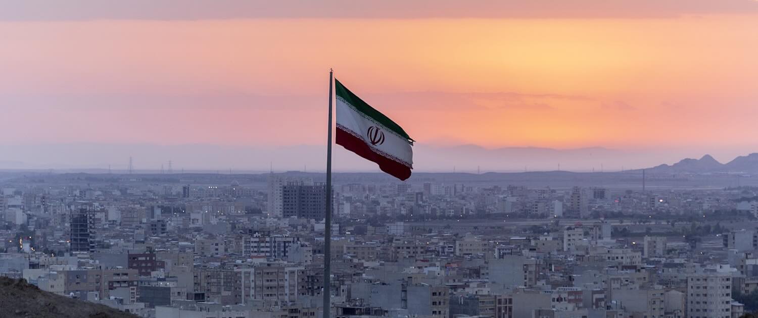 Photo of Iran flag with city in the background