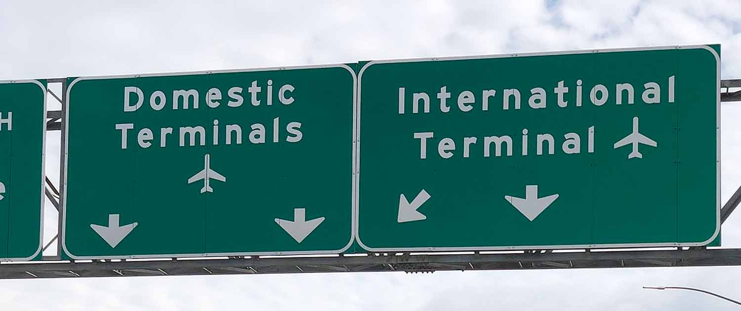 Photo of highway signs pointing to domestic and international terminals