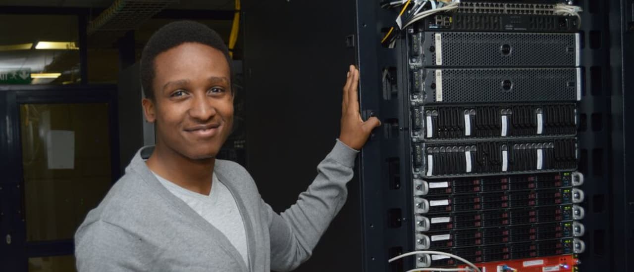 Photo of a person standing in front of a network rack containing an IXP switch