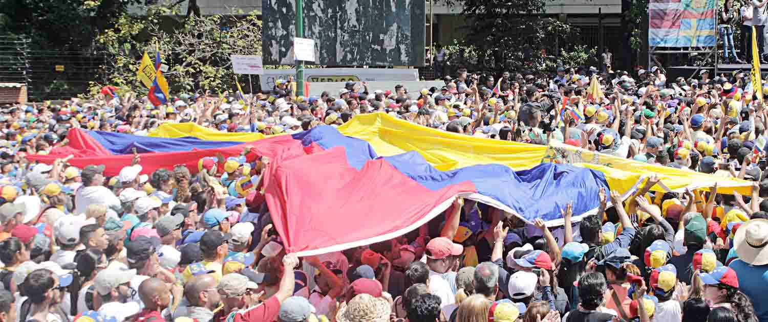 Photo of a crowd holding a large flag of Venezuela