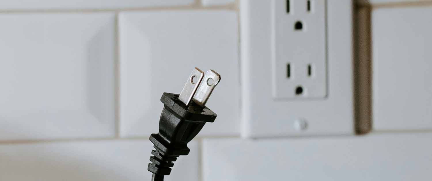 Photo of an emplty power plug and a person holding a power cable