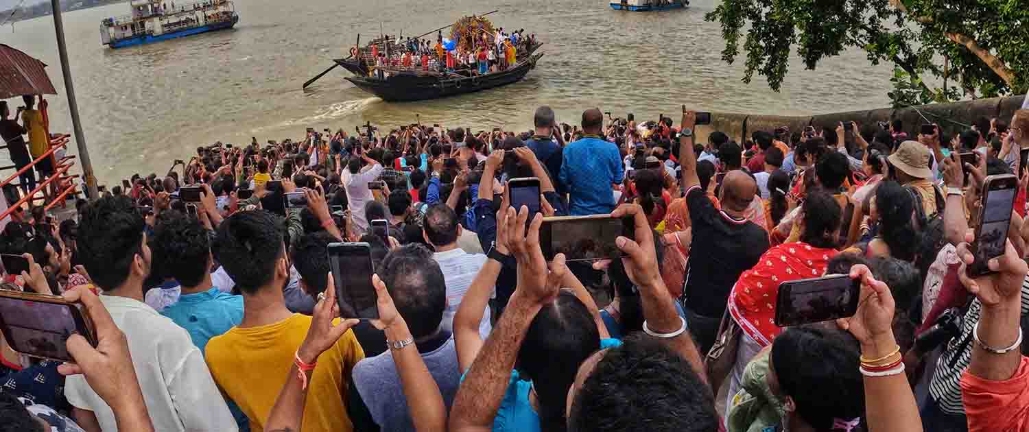 A crowd of people taking photos along a river in India