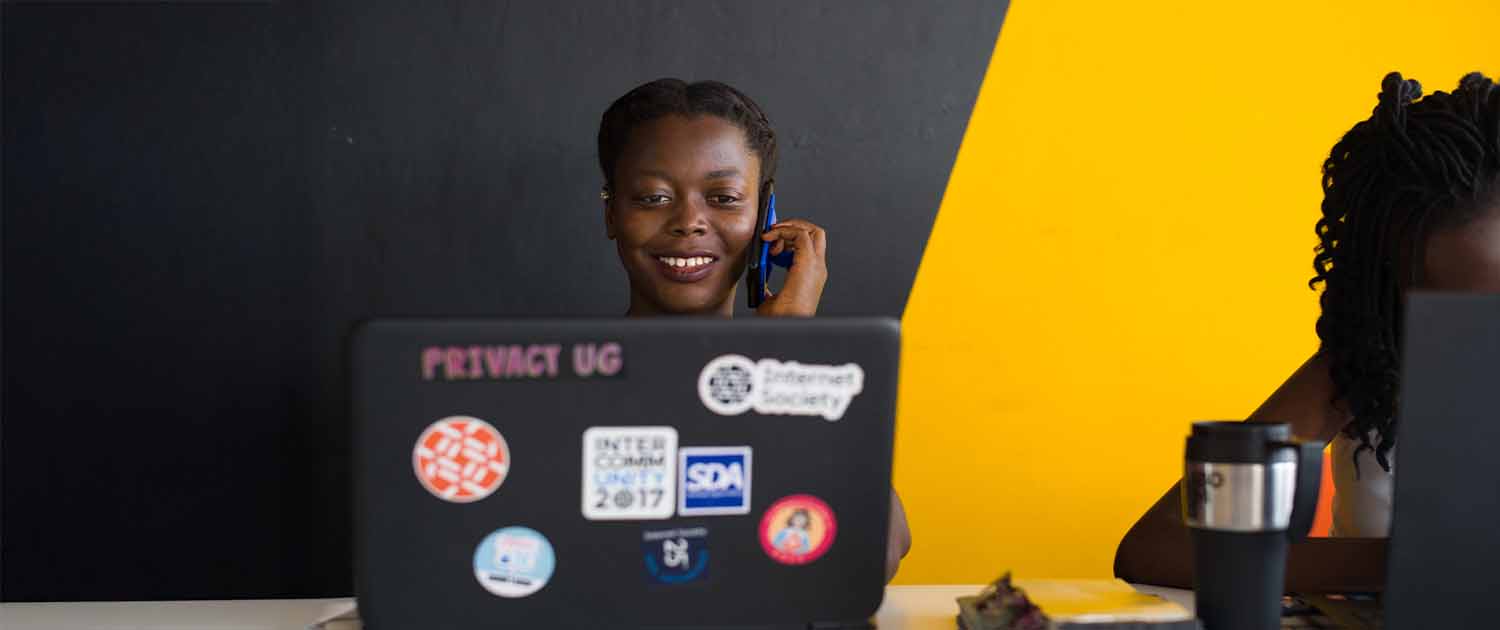 Photo of a woman working at her computer while talking on a phone