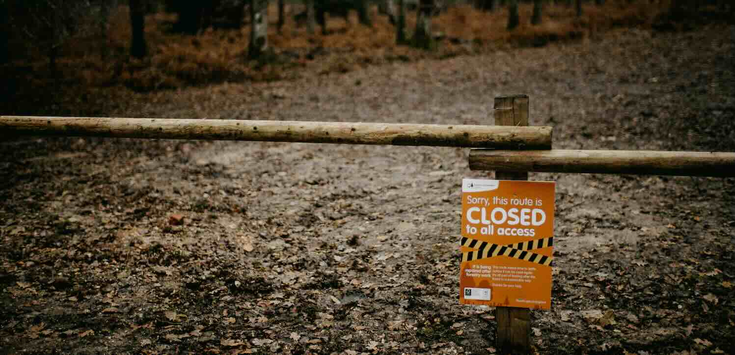 Photo of a barrier in front of a path with a sign saying 'route closed'