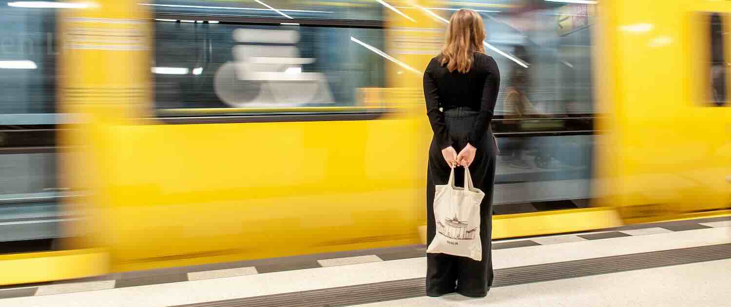Photo of a woman waiting at a platorms edge as a train goes past
